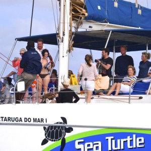 Group of people relaxing on a sailing boat with blue canopy.