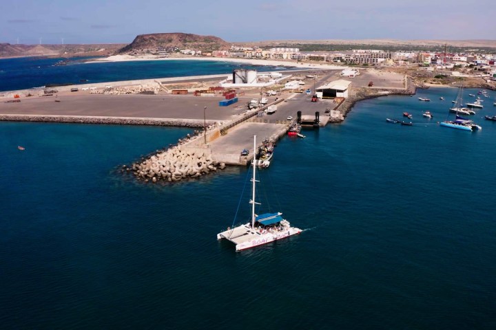 Aerial view of a harbor with boats and a distant town on shore.