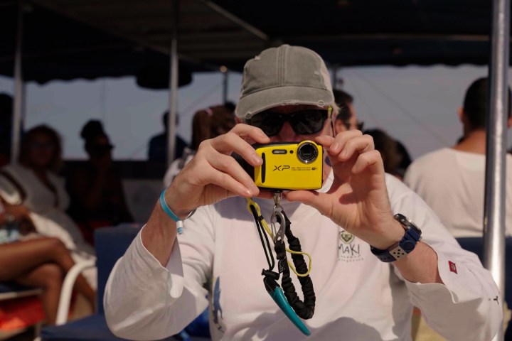 Person on a boat taking a photo with a yellow camera.